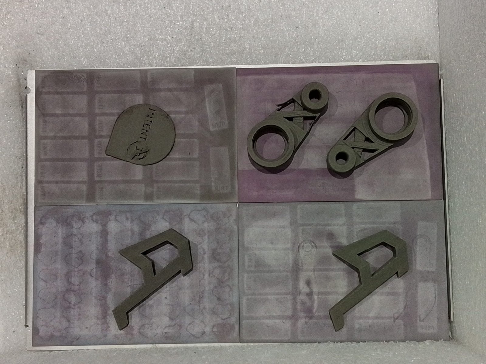 Green-state 3D printed metal parts on ceramic setter plates during the debinding and sintering stage at Intent3D